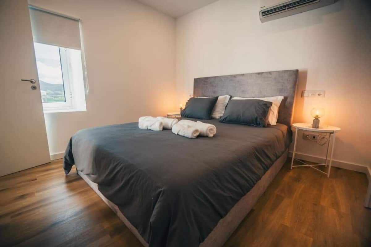 Ein Schlafzimmer mit einem großen Bett, einem Nachttisch mit Lampe und einem Fenster mit Blick.