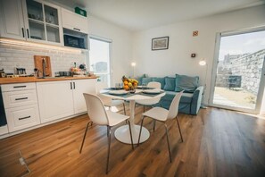 Een moderne keuken met witte kasten, een houten aanrecht en een eethoek met een ronde tafel en stoelen.