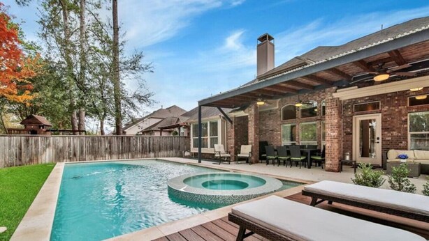 Um quintal com piscina, área de estar externa e varanda coberta.