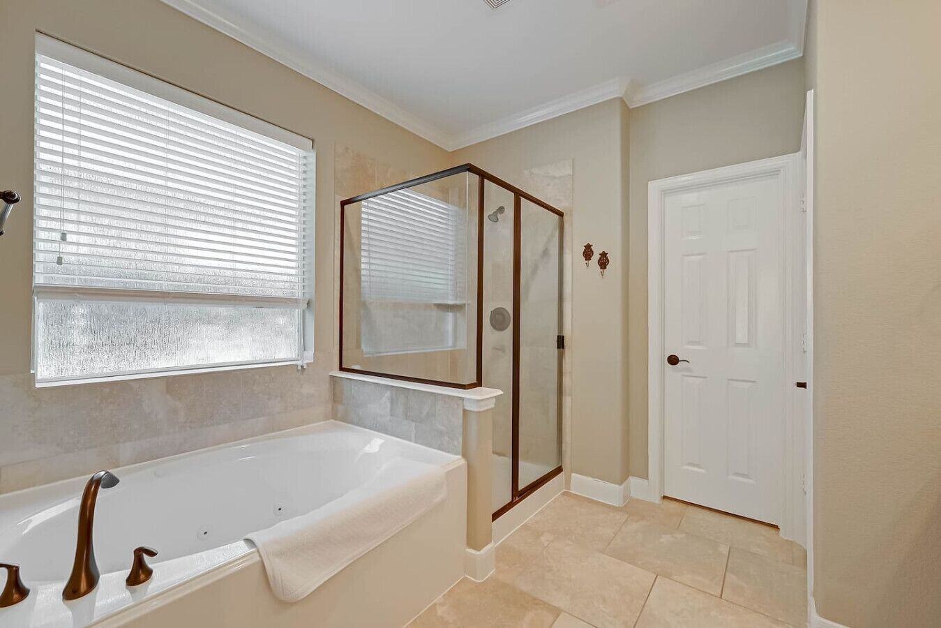A bathroom with a bathtub, a shower enclosure, and a door.