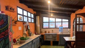 A kitchen with a green patterned floor, a window with a view, and a wooden ceiling. - Kasa Kiwi Hostel and Travel (Quetzaltenango)