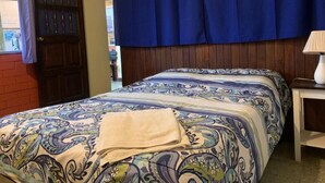 A bedroom with a bed, a nightstand, a lamp, a window with curtains, and a door. - Kasa Kiwi Hostel and Travel (Quetzaltenango)