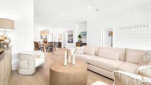 Ein geräumiger Wohnbereich mit einem runden Couchtisch, einem beigen Sofa und einem modernen Esstisch-Set.