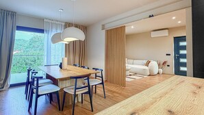 Een modern interieur met een eethoek, een bank en uitzicht door een raam.