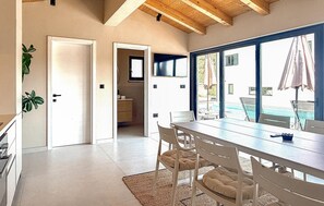 A modern kitchen with white cabinets, a wooden ceiling, and a view of a pool outside. - Luxurious home in Labin (Labin)