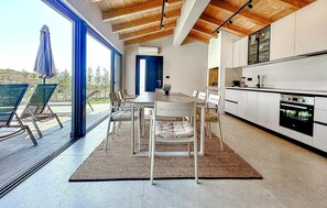 A modern kitchen with a built-in oven and a dining area with a table and chairs. - Luxurious home in Labin (Labin)
