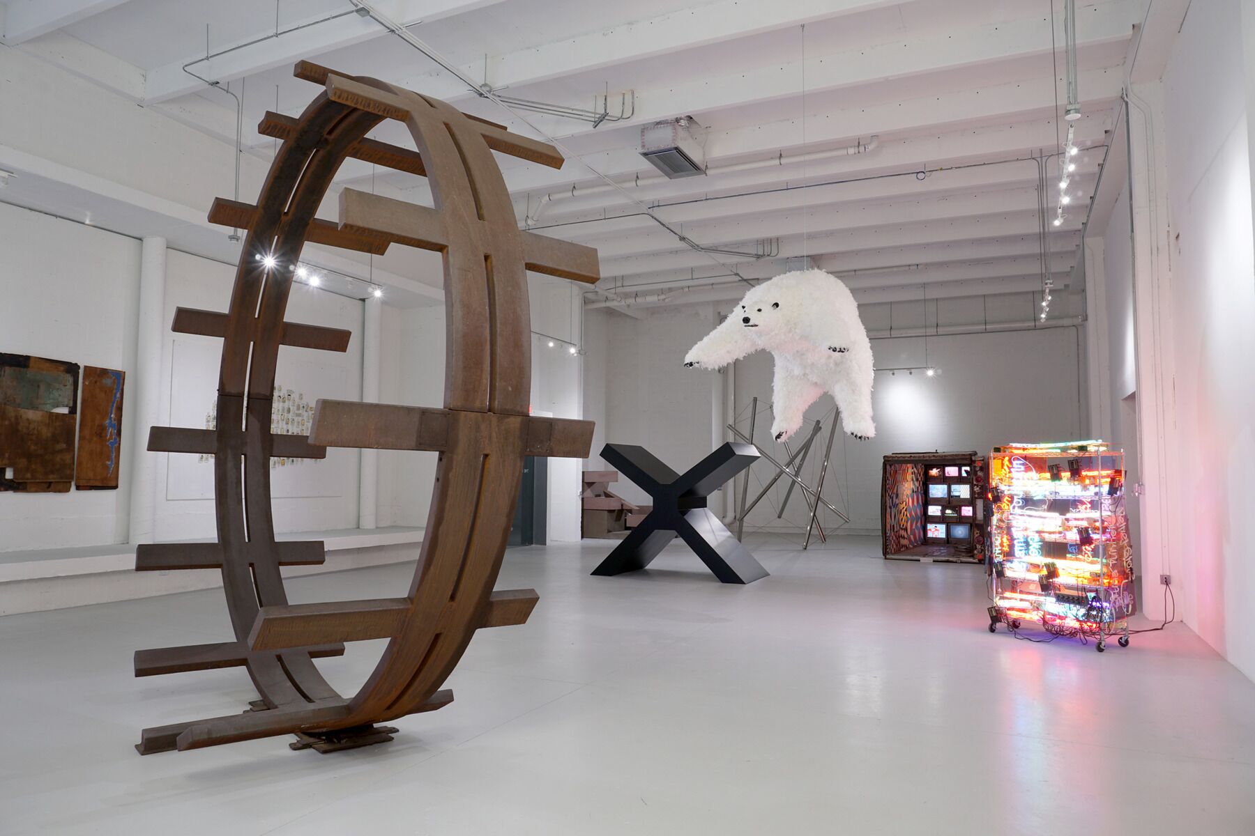 Een kunstinstallatie met een grote houten constructie, een beeldhouwwerk van een witte beer en een neonverlichte presentatie.