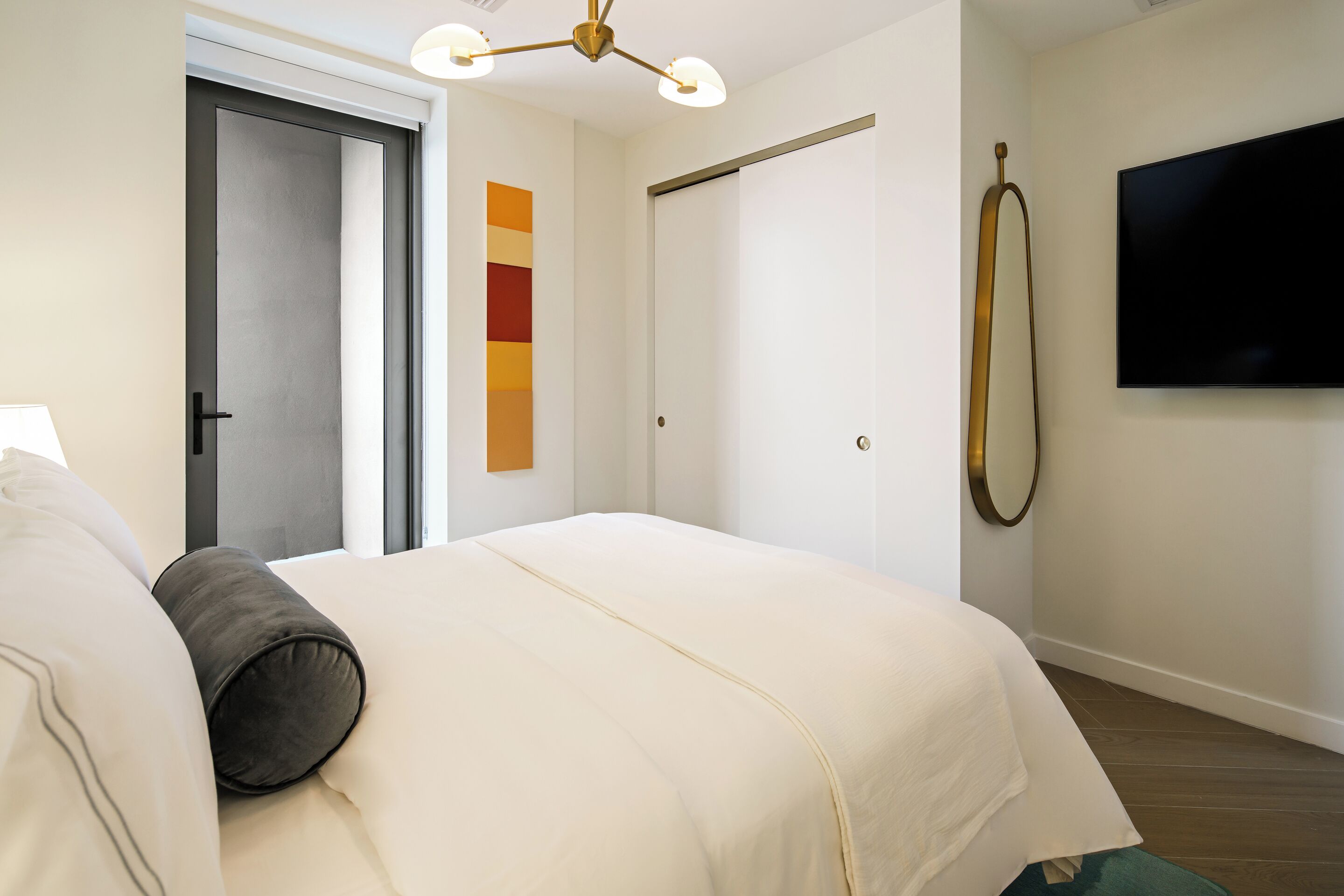 Una habitación de hotel con una cama, un televisor, una puerta y un televisor montado en la pared.