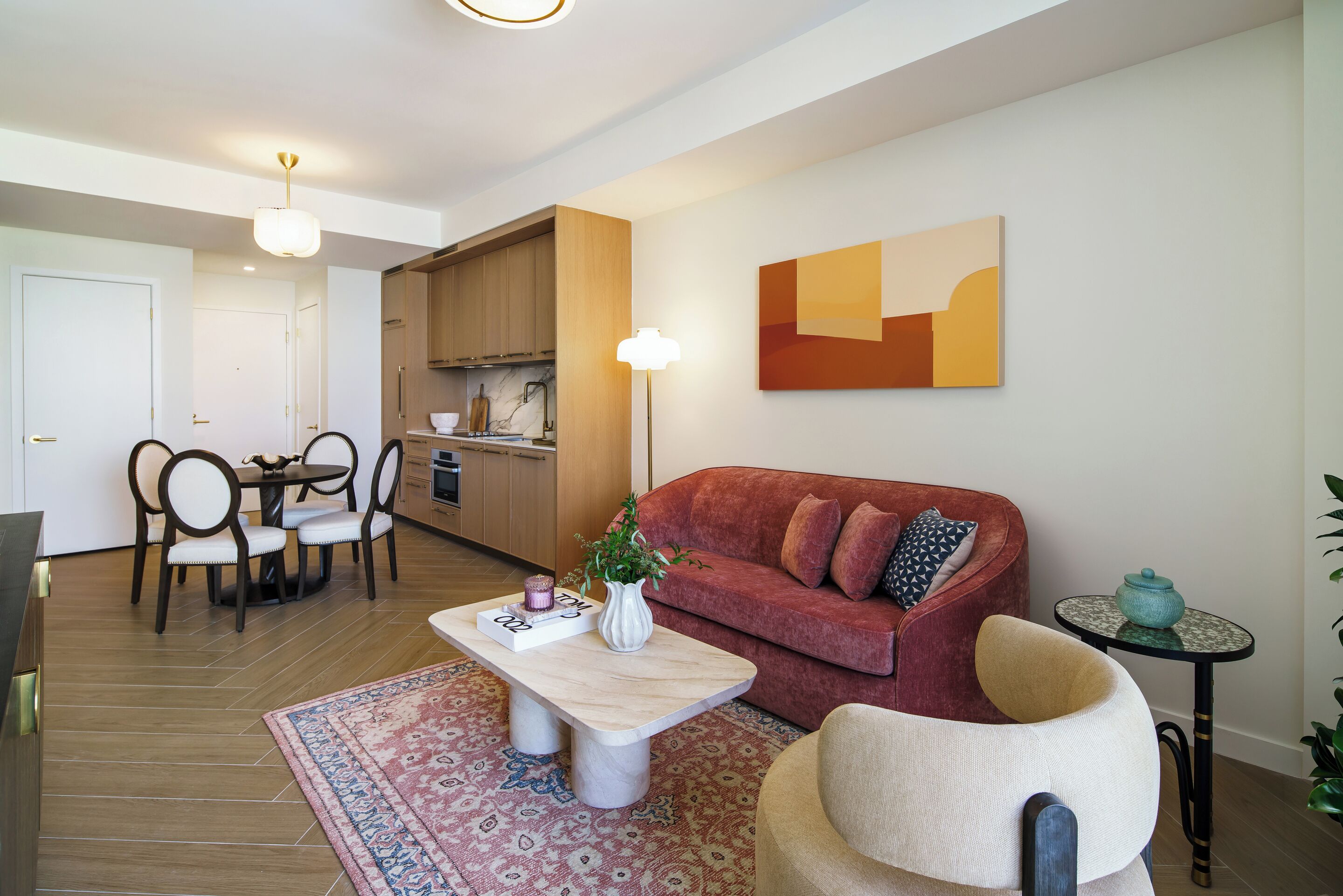 A modern living room with a red sofa, a coffee table, and a dining area with chairs and a table.