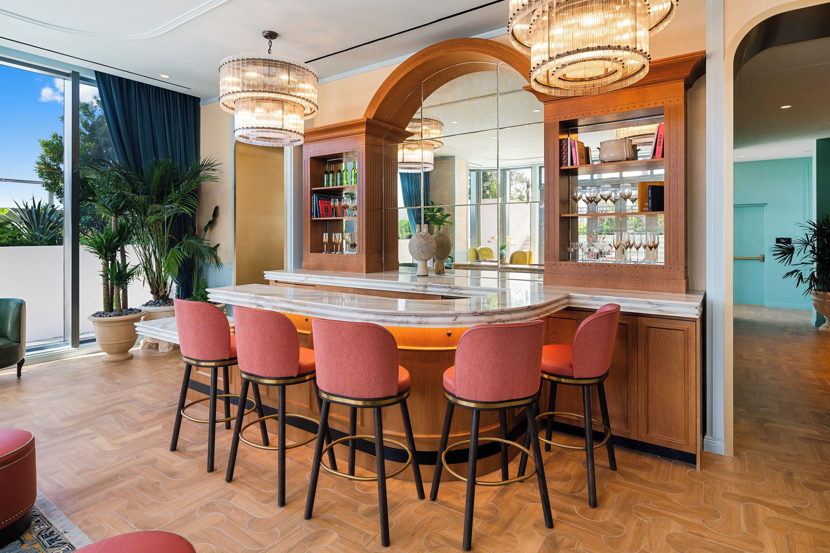 A bar area with a marble countertop, red bar stools, and a mirrored wall.