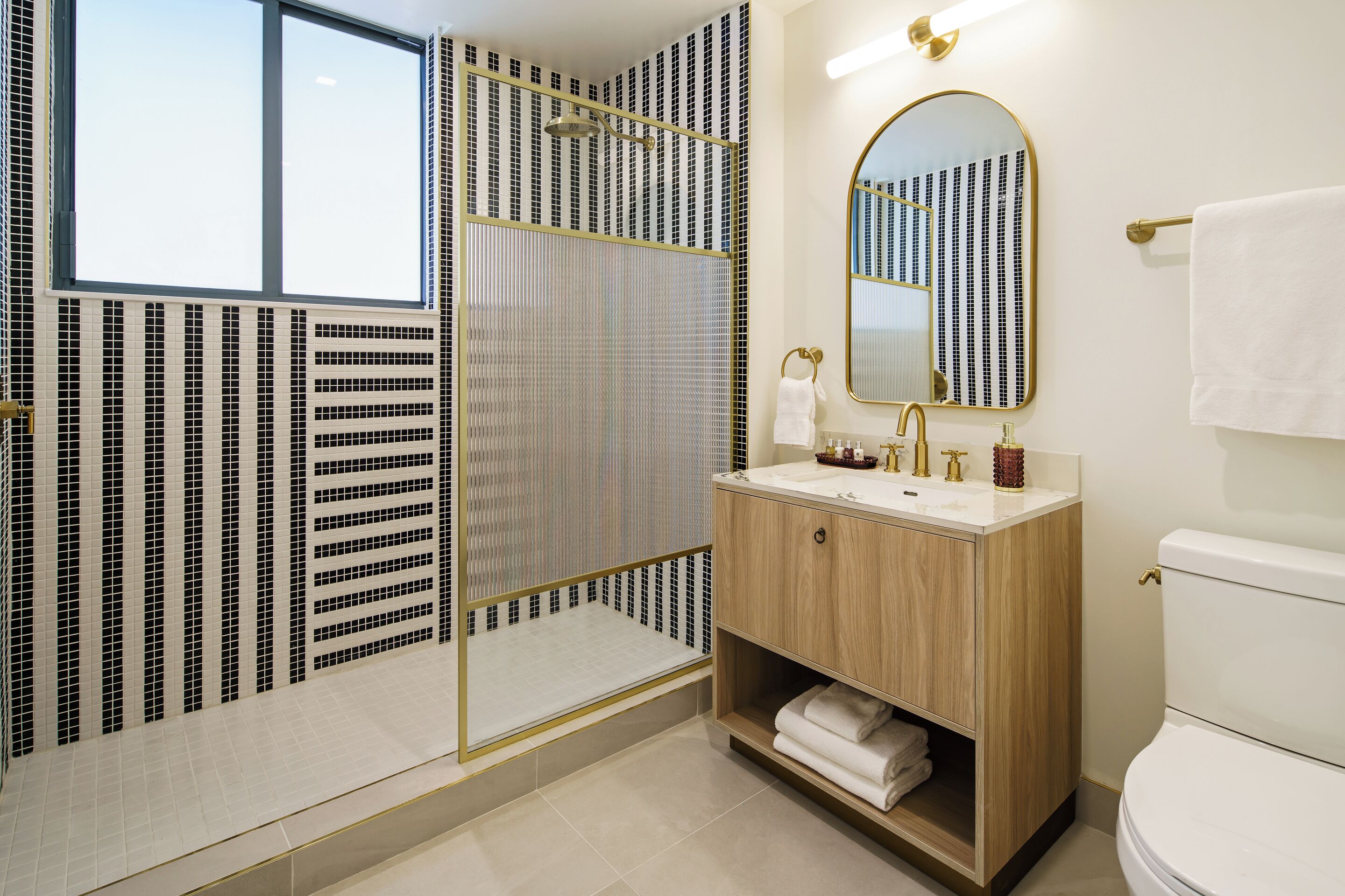 Un baño con ducha, lavabo, inodoro y espejo.