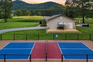 A tennis court with a house in the background. - Private Pickleball Court, Hot Tub and Fire Pit (Arden)