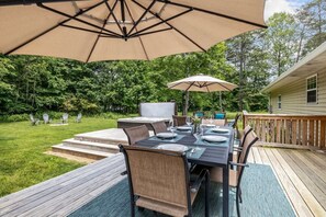 An outdoor deck with a dining table, chairs, and a large umbrella. - Private Pickleball Court, Hot Tub and Fire Pit (Arden)