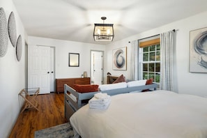 Un dormitorio con cama, cómoda, espejo y ventana con cortinas.