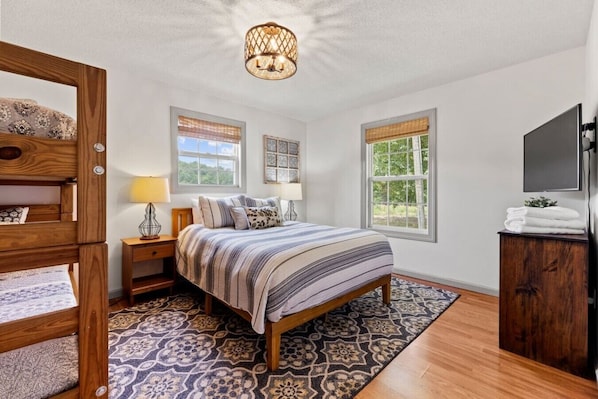 A bedroom with a bed, bedside tables, a lamp, a TV, and a window. - Private Pickleball Court, Hot Tub and Fire Pit (Arden)