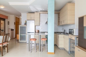 A modern kitchen with light wood cabinets, a granite countertop, and two bar stools.