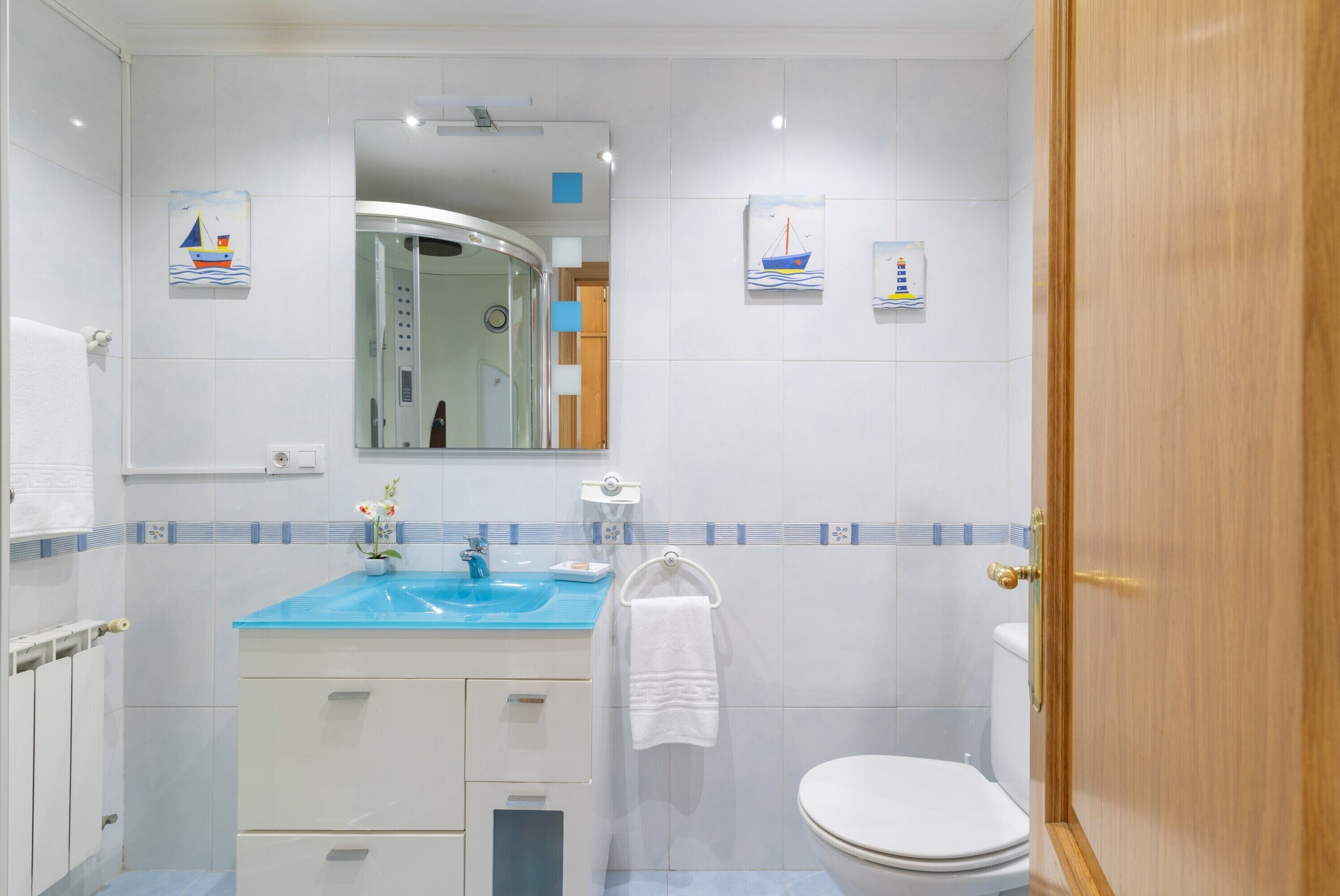 A bathroom with a sink, mirror, toilet, and towel rack.