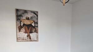 Een slaapkamer met een houten hoofdbord, een wit gebogen beddegoed en een enkel groen kussen.