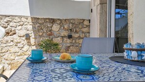 Ein Tisch mit einer blau-weißen Tischdecke, einer blauen Schüssel, einem Teller mit einem Gebäck und einer blauen Tasse.
