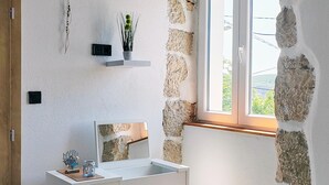 Ein Badezimmer mit Steinwand, Waschbecken in Weiß und einem Spiegel.
