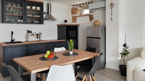 Eine moderne Küche mit dunklen Schränken, einem Holztisch und einem Kühlschrank.