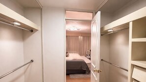 Ein schmaler Flur mit Holzboden führt zu einem Schlafzimmer mit Bett und Nachttisch.