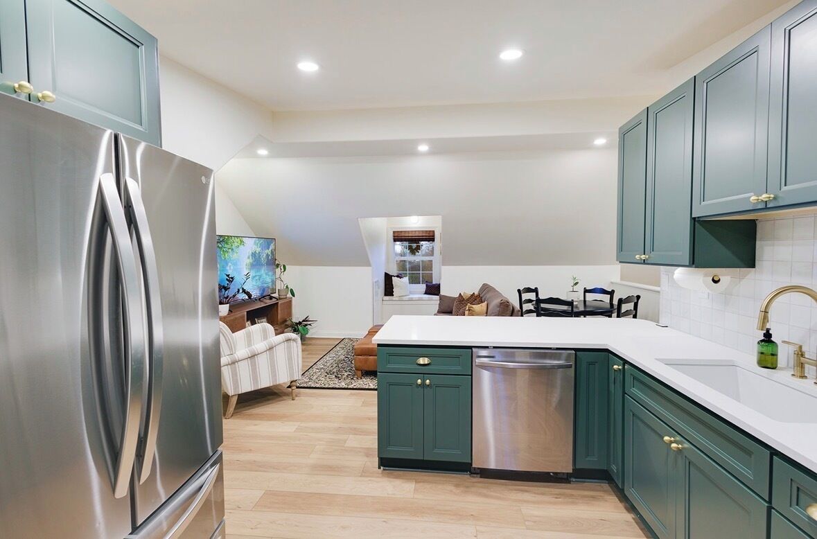 Une cuisine moderne avec des meubles de couleur turquoise, des appareils en acier inoxydable et un plan de travail blanc.