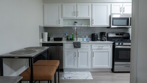 Eine moderne Küche mit weißen Schränken, einer Mikrowelle, einem Backofen und einer Kaffeemaschine.
