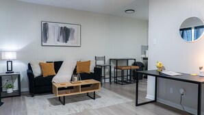 Ein modernes Wohnzimmer mit einer schwarzen Couch, einem Holztisch und einem minimalistischen Design.