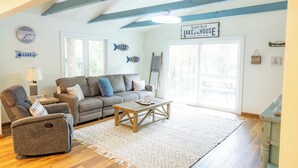 A living room with a sofa, armchair, and coffee table, a clock, and a sign reading 'Lake House'.