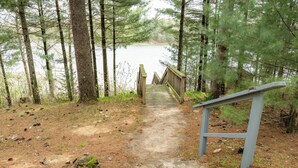 A wooden pathway leading to a lake surrounded by trees.