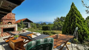 A rustic outdoor seating area with a brick oven, wooden furniture, and a view of mountains. - Amazing apartment in Moscenicka Draga with WiFi (Moscenicka Draga)
