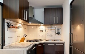 A modern kitchen with dark wooden cabinets, a stainless steel sink, and a gas stove. - Amazing apartment in Moscenicka Draga with WiFi (Moscenicka Draga)