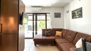 A modern living room with a brown sectional sofa, a flat-screen TV mounted on the wall, and a sliding glass door leading to an outdoor area. - Amazing apartment in Moscenicka Draga with WiFi (Moscenicka Draga)