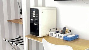 Kompakti ja moderni keittokomero, jossa on kahvinkeitin, pieni jääkaappi ja kahvitiskin kyltti.