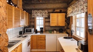 Una cocina compacta con armarios de madera, un microondas, una cafetera y un lavabo.