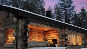 Una cabaña de troncos con un ventanal grande y una chimenea.