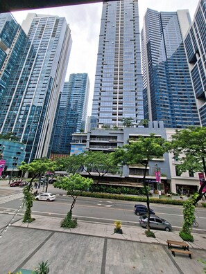 A modern urban street with tall buildings, a crosswalk, and a bench. - MySuites 2Go 24k Cozy 1-bedroom condo in peaceful Taguig with Balcony ,CLEANED (Taguig)