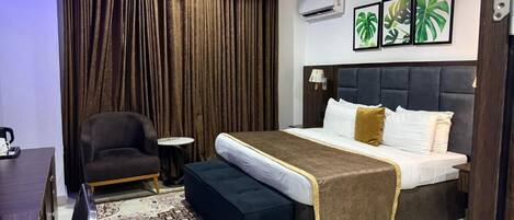 A bedroom with a bed, a chair, a small table, and a patterned rug.