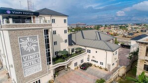 Un bâtiment appartenant à la chaîne Vinpy Hotels, avec une grande enseigne, un espace extérieur abrité avec des sièges et un parking.