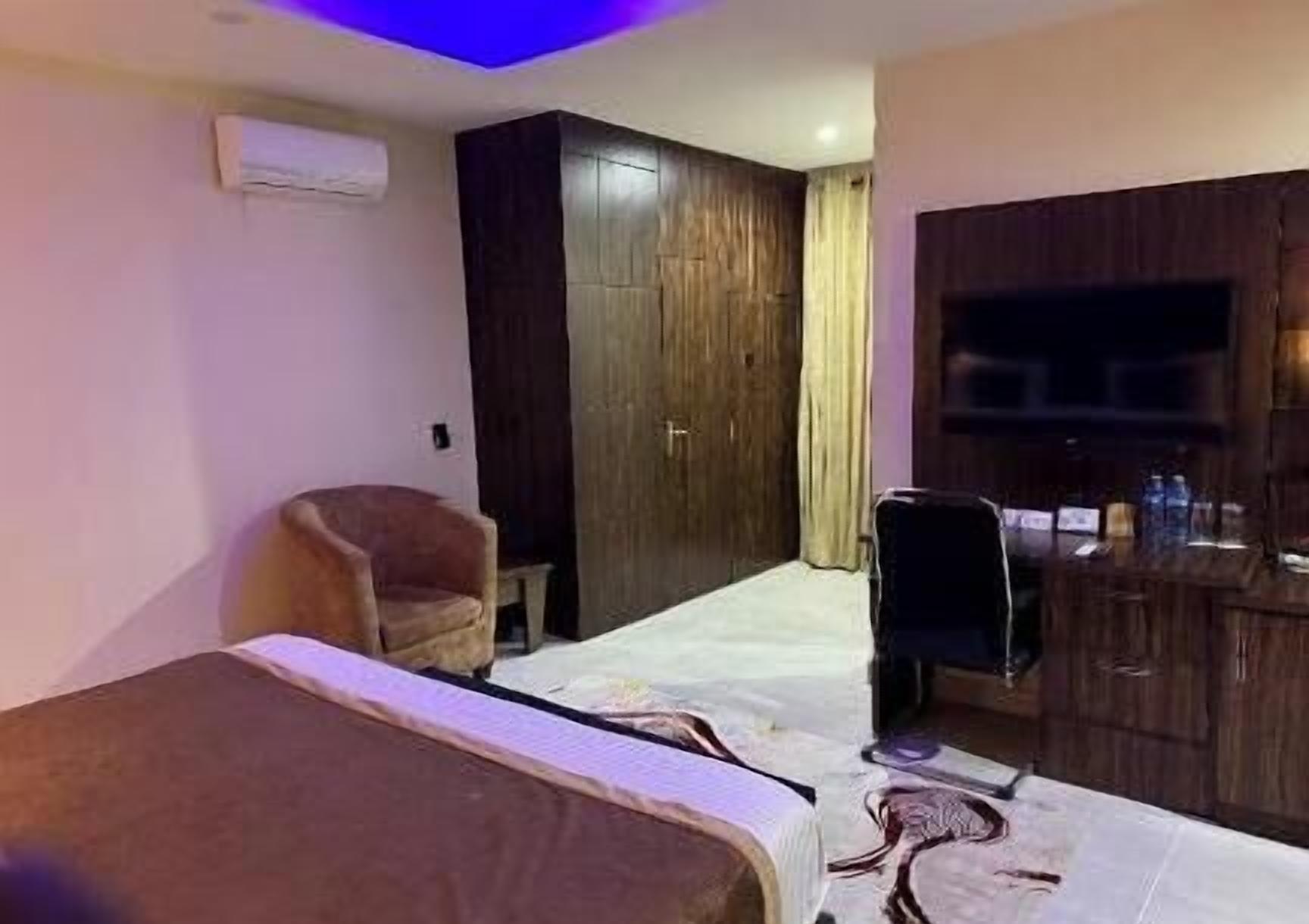 Une chambre d’hôtel avec un lit, une chaise, un bureau et une armoire.