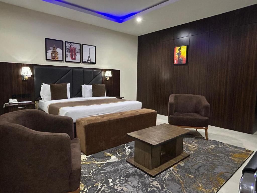 A hotel room with a large bed, two bedside tables, a sofa, a chair, and a coffee table.