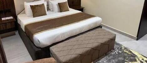 A hotel room with a large bed, two bedside tables with lamps, a headboard, and two wall-mounted paintings.
