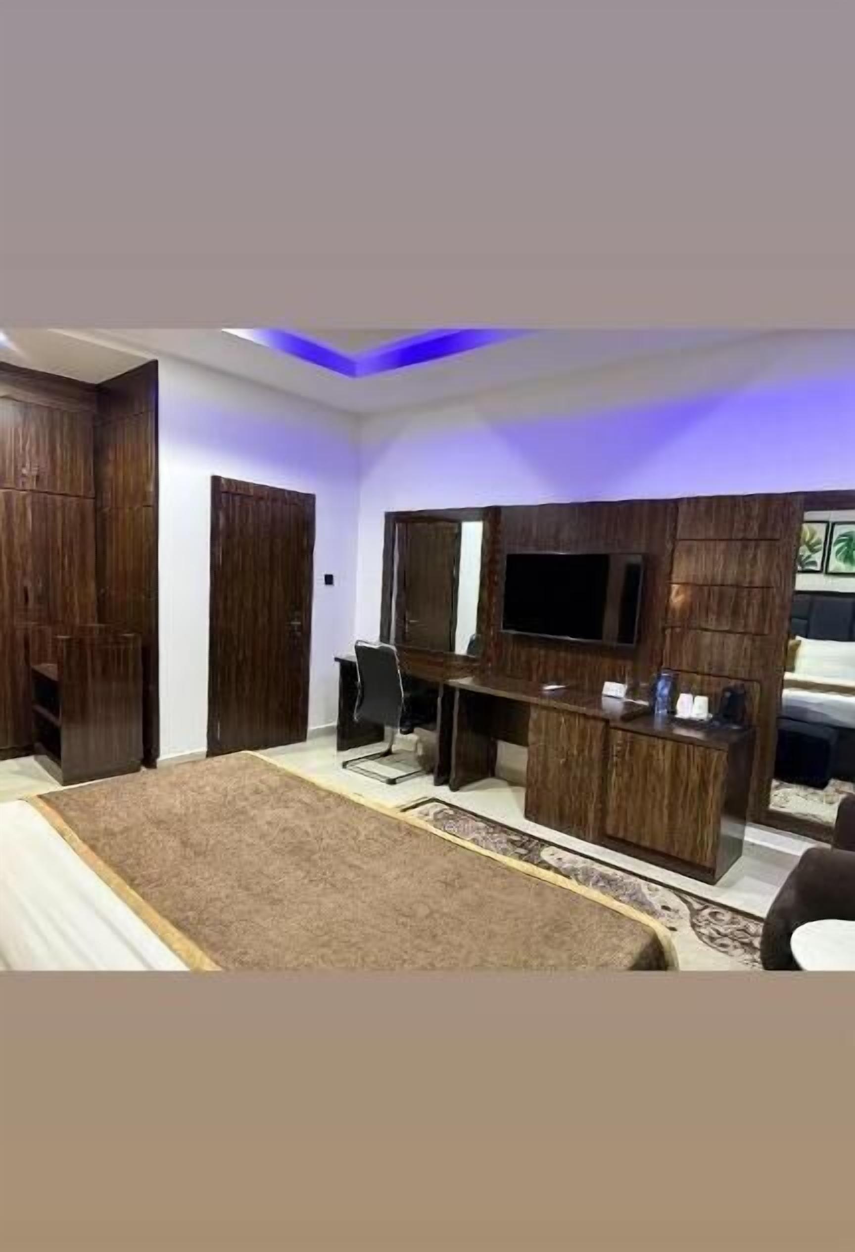 A bedroom with a bed, a desk, a chair, a TV, and built-in wardrobes.