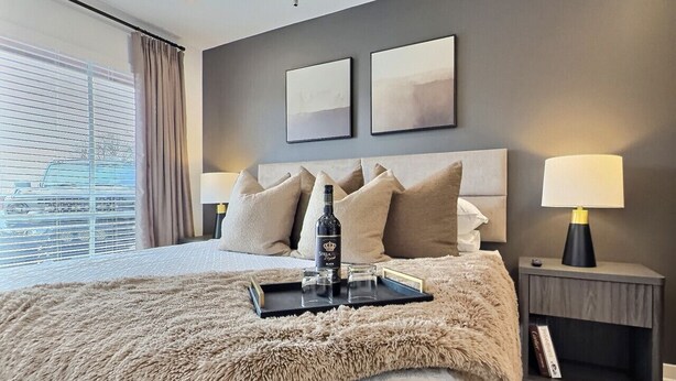 Et moderne hotelværelse med en stor seng, et sengebord med lampe og et billede på væggen.