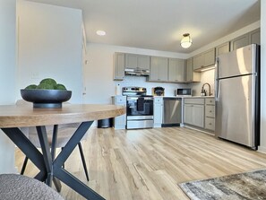 Una cocina moderna con suelo de madera, electrodomésticos de acero inoxidable y armarios de colores claros.