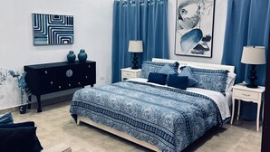 Ein Schlafzimmer mit einem Bett, Nachttischen, einer Kommode und einem Gemälde.
