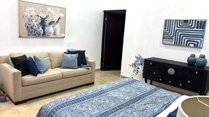 Ein modernes Wohnzimmer mit einem beigen Sofa, einem gemusterten Teppich und einer schwarzen Kommode mit Dekorationselementen.