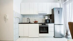 A modern kitchen with white cabinets, a black countertop, a stainless steel refrigerator, a microwave, and an oven. - 1 bedroom stunning apartment in Podstrana (Podstrana)