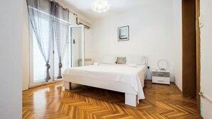 A bedroom with a large bed, a bedside table with a mirror, and a window with curtains. - 1 bedroom stunning apartment in Podstrana (Podstrana)